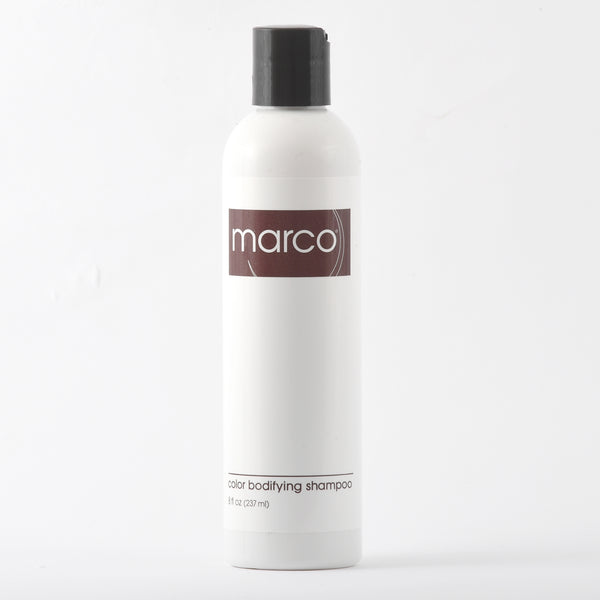 A bottle of "marco® color bodifying shampoo" with a white label and a brown cap on white background